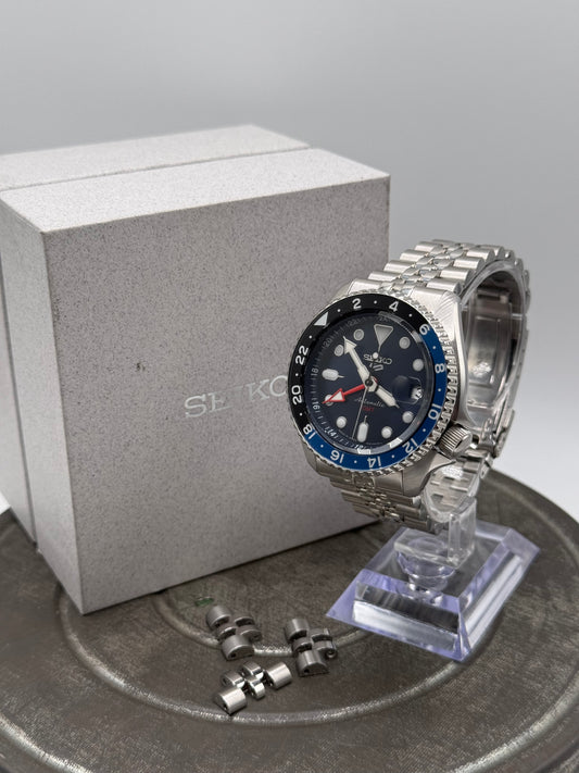 Seiko 5 Sports GMT Automatic Watch – Black Dial, Blue & Black Bezel, Stainless Steel Jubilee Bracelet with Box